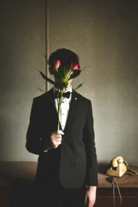 a person holds long stemmed roses, hiding their face